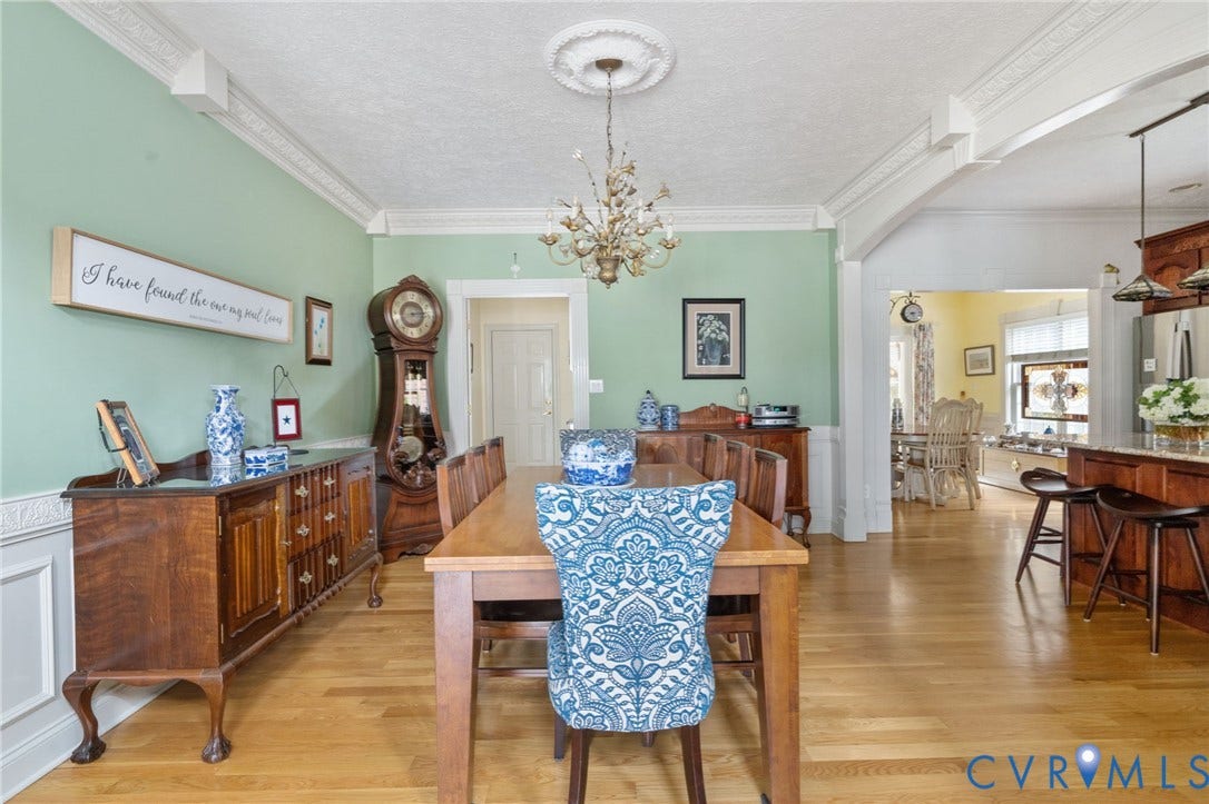 Dining area featuring light wood-finish flooring, wainscoting, and decorative crown molding