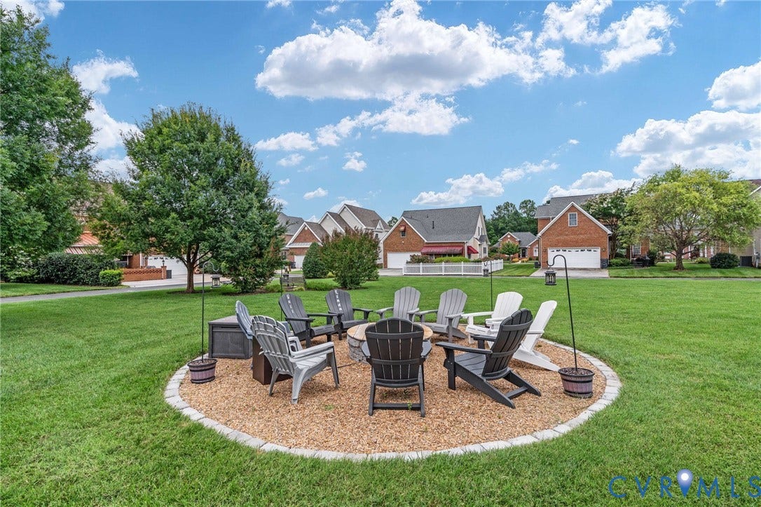 Manicured lawn with a defined fire pit area, featuring a decorative stone border and wood chip ground cover