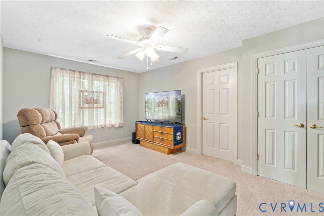 Carpeted room featuring a ceiling fan with integrated lighting, a window with sheer curtains, a six-panel door, and a bi-fold six-panel door