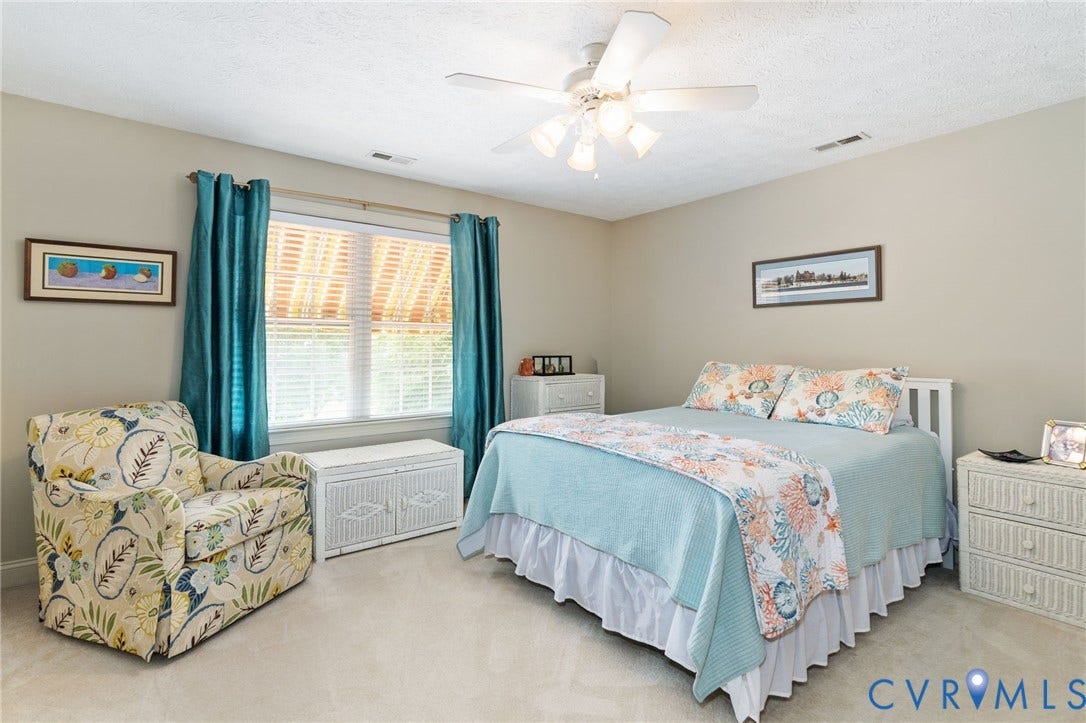 Carpeted room with a ceiling fan, a window featuring blinds and drapes, and neutral wall paint