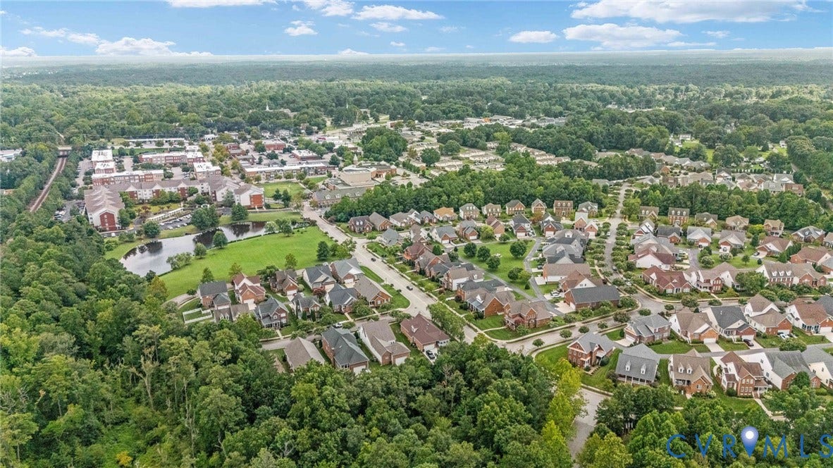 Aerial perspective showcasing a residential community with varied architectural styles, mature trees, and a central pond feature