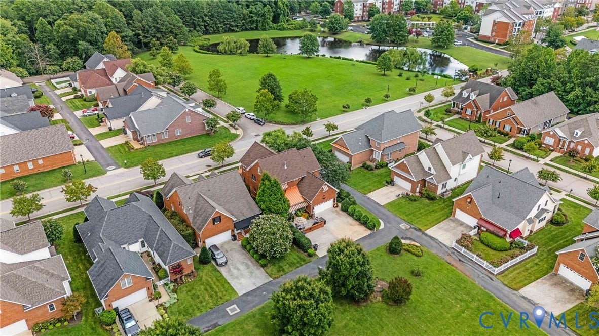Aerial perspective of a residential community featuring single-family homes with brick and siding exteriors, attached garages, and individual driveways
