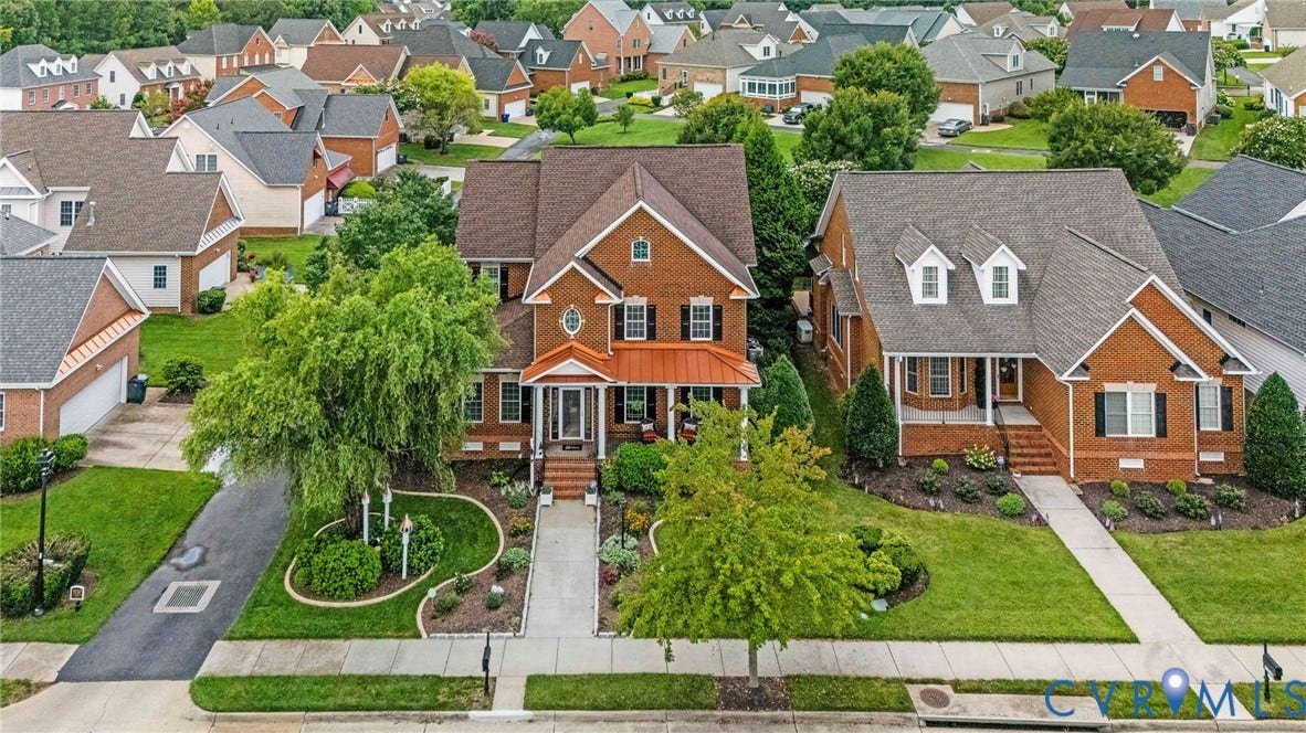 Traditional brick home featuring a covered front porch, dormer windows, and a multi-level roofline