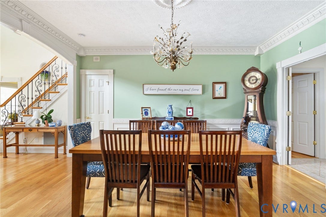 Formal dining space featuring hardwood flooring, intricate crown molding, a decorative chandelier, and wainscoting details