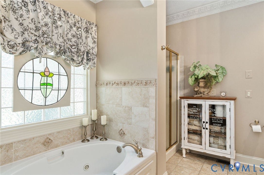 Soaking tub with tile surround, framed by a window with decorative stained glass