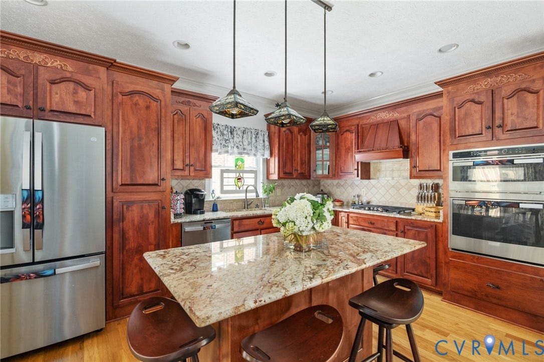 Kitchen featuring hardwood flooring, extensive wood cabinetry with crown molding, and a central island with a light-toned countertop