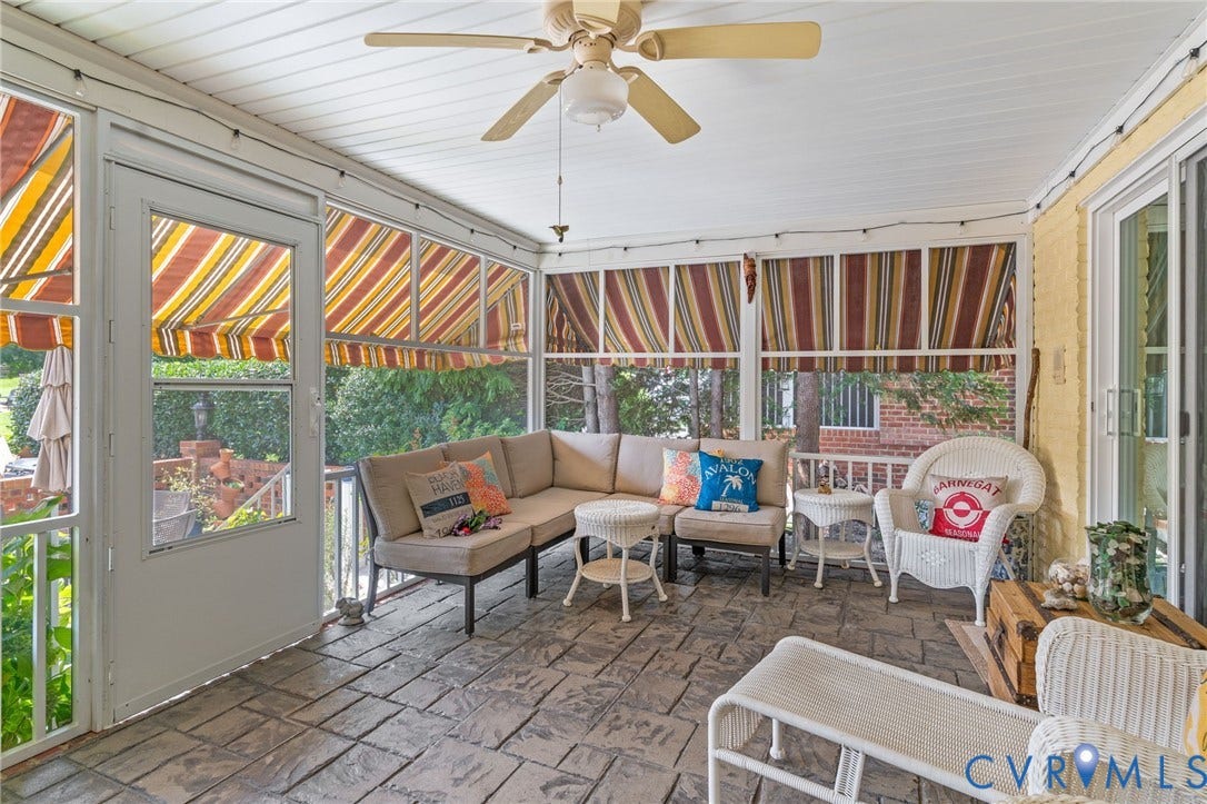 Screened porch featuring a textured concrete floor, ceiling fan, and sliding glass door access