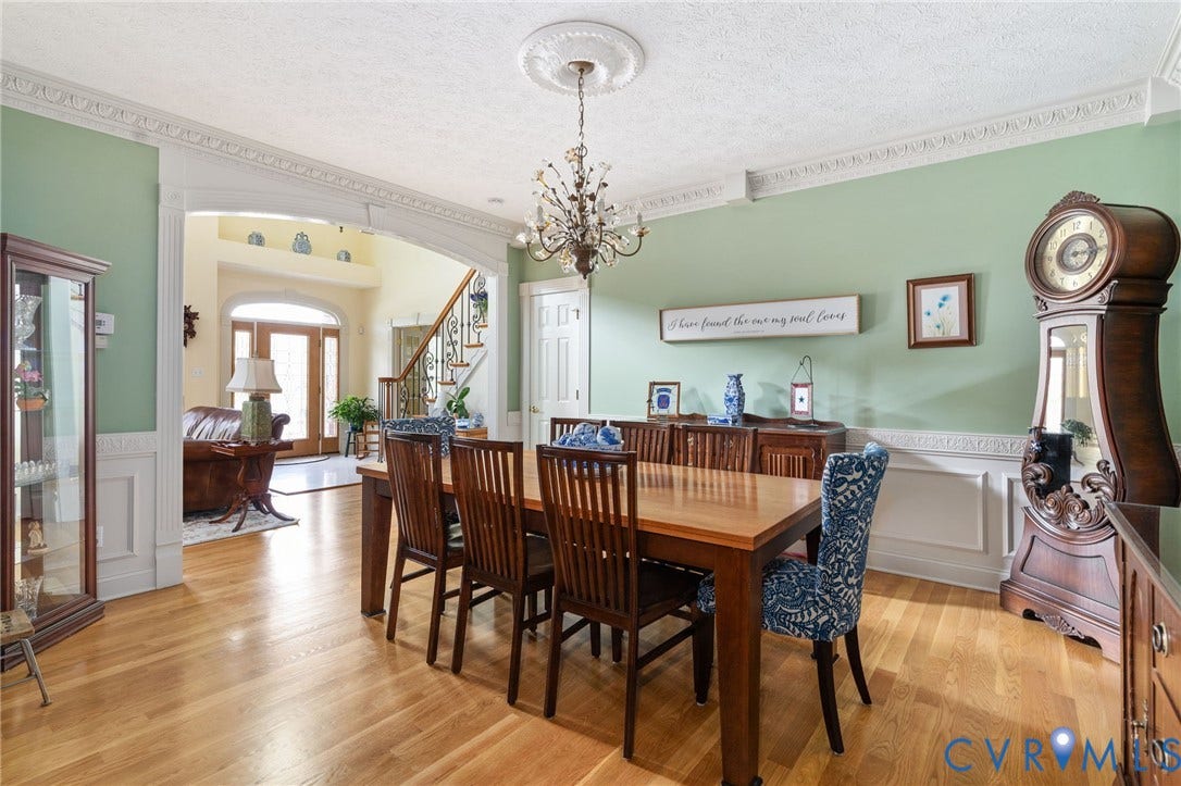 Formal dining area featuring hardwood flooring, intricate crown molding, wainscoting, a decorative ceiling medallion, and an ornate chandelier
