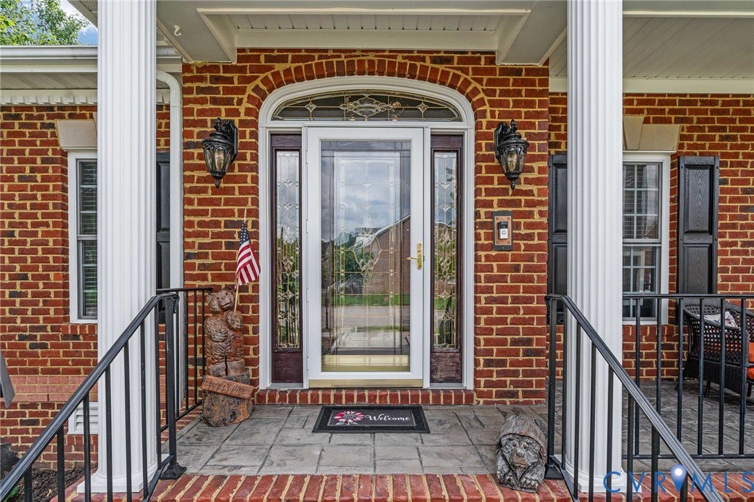 Brick exterior featuring a portico with white fluted columns