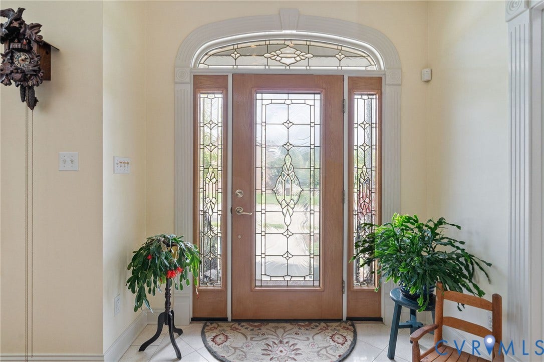 Entryway featuring a wood-panel door with decorative leaded glass, flanked by matching sidelights and a transom window