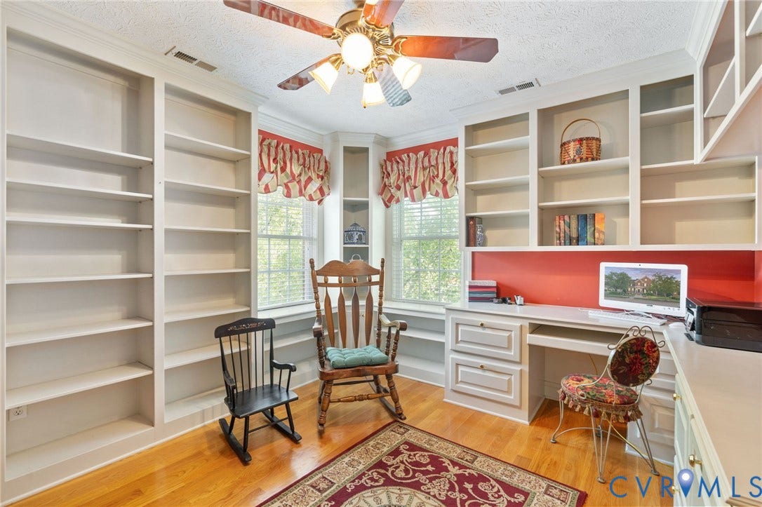 Room featuring extensive built-in shelving, a built-in desk, and hardwood flooring