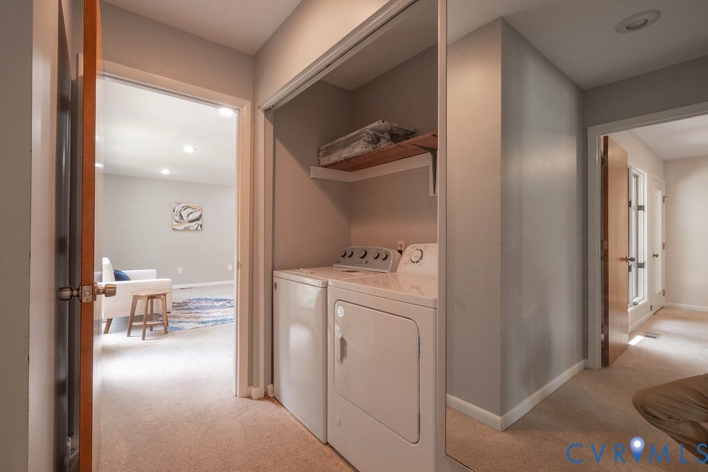 Dedicated laundry area featuring a washer and dryer, accompanied by an overhead wood-finish shelf