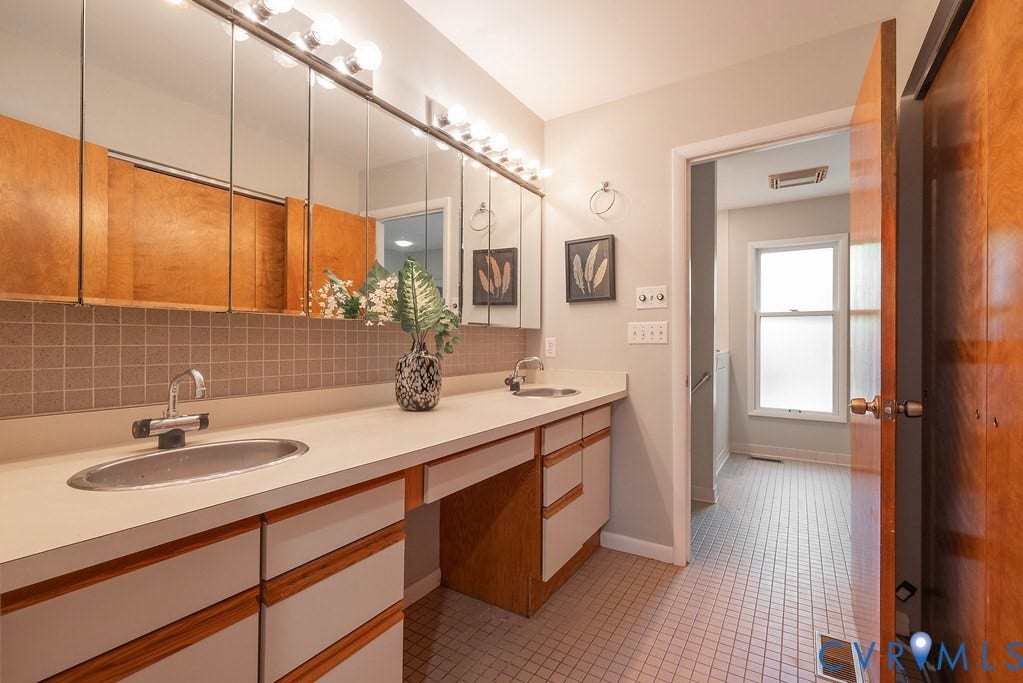 Dual sink vanity with ample countertop space, integrated cabinetry, full-width mirror, and mosaic tile backsplash