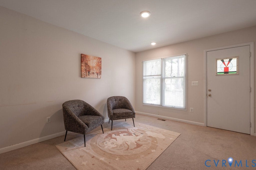 Recessed ceiling lighting, front entry door with a stained glass insert, and a large double window
