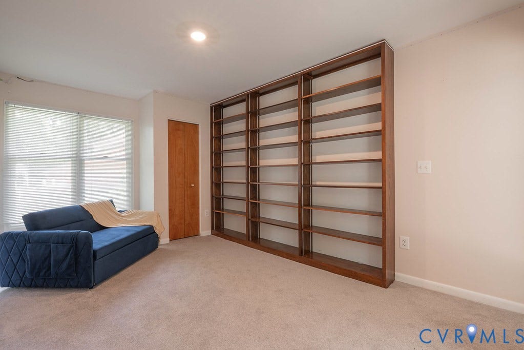 Built-in shelving unit, neutral-toned carpeting, and a recessed ceiling light