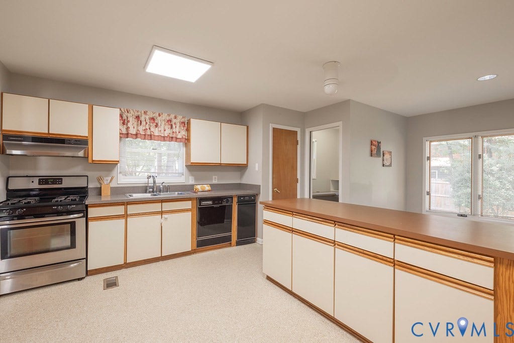 Kitchen with ample cabinetry, stainless steel range, built-in dishwasher, and a large central island