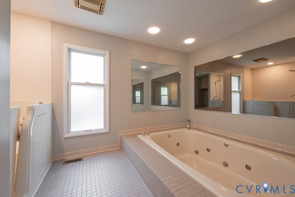 Jetted soaking tub with tiled surround, walk-in tub with textured glass window, and recessed lighting