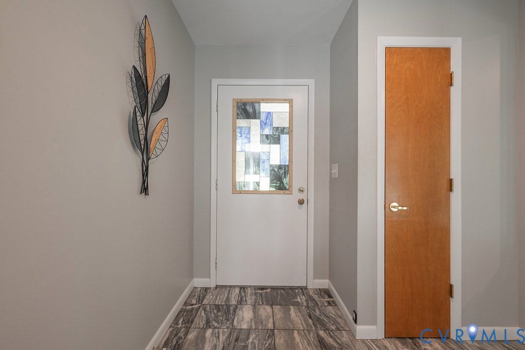 Entryway featuring a white door with a stained glass insert, wood-finish flooring, and a flush-mounted light switch