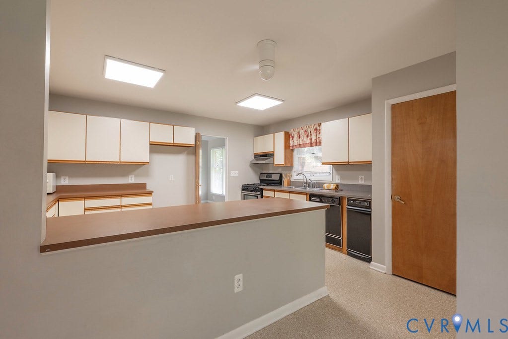 Kitchen featuring abundant cabinetry, dark countertops, integrated sink, and black appliances