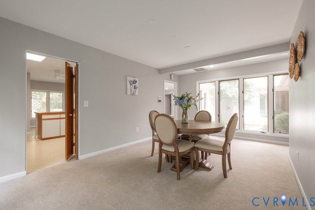 Recessed lighting, wood-finish flooring in adjoining room, light gray wall paint, large windows, light carpet flooring