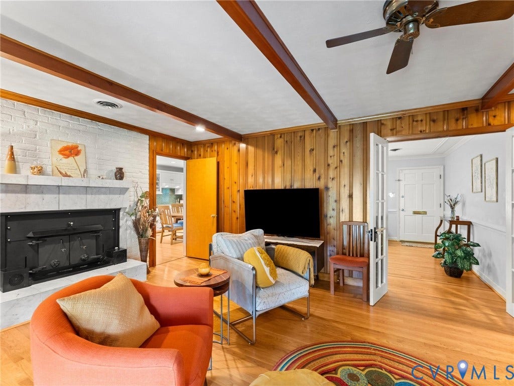 Living area featuring a white-painted brick fireplace with a stone hearth and mantel