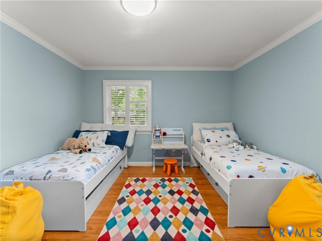 Bright and cheerful shared bedroom featuring soft blue walls, white ceiling trim, and hardwood flooring