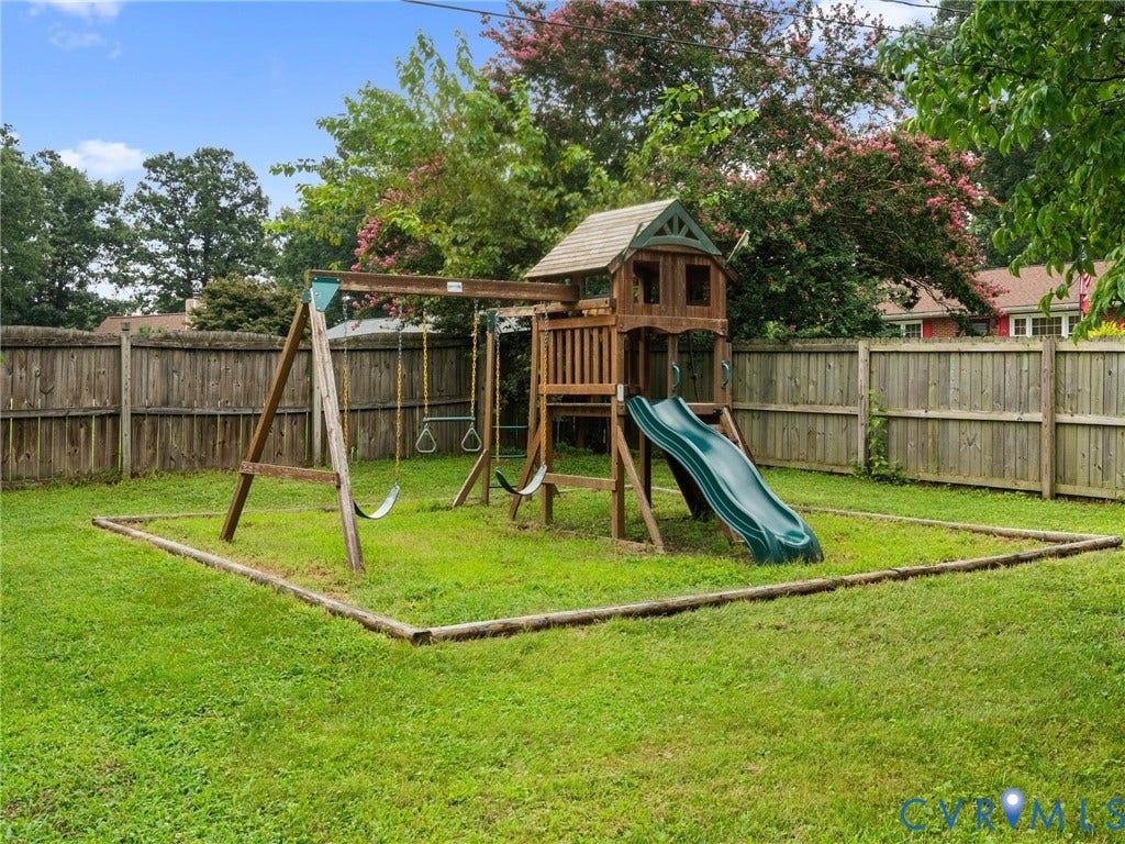 Expansive backyard featuring a built-in wooden playset with a slide and swing components