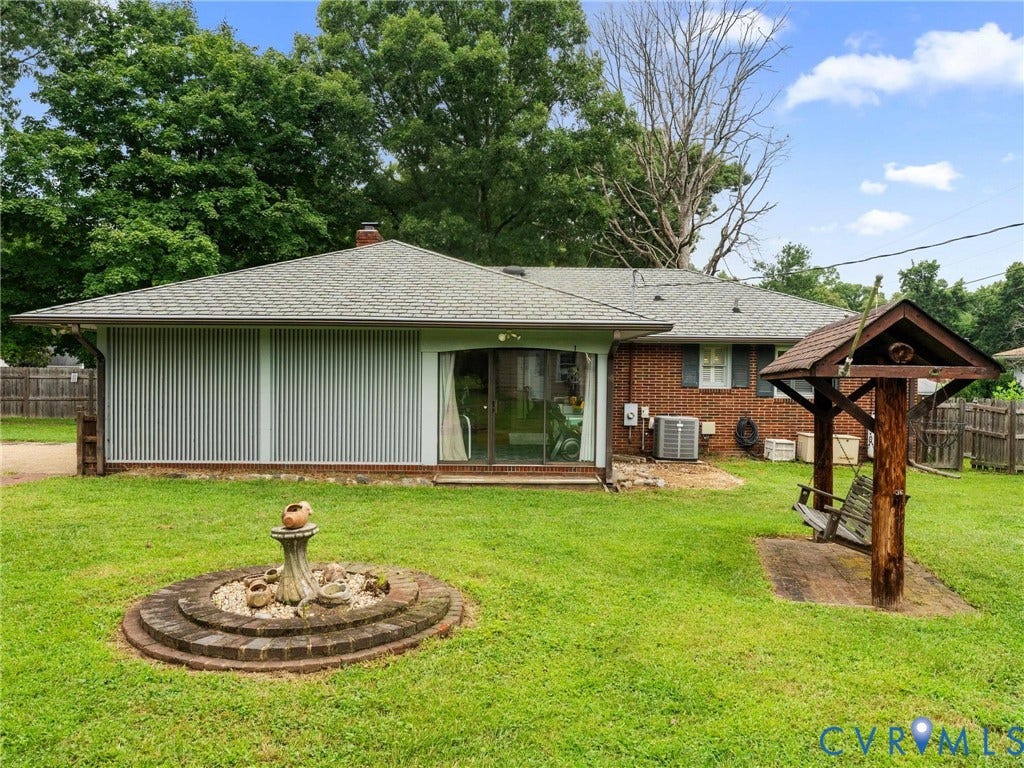 Expansive backyard featuring a manicured lawn, brick exterior, and a built-in outdoor swing structure
