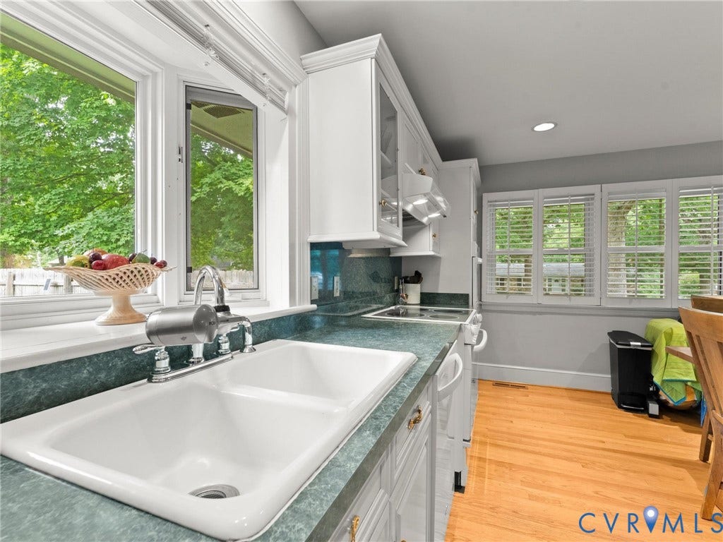 Kitchen featuring a double basin sink with chrome faucet, green patterned countertop, white cabinetry, and wood-finish flooring