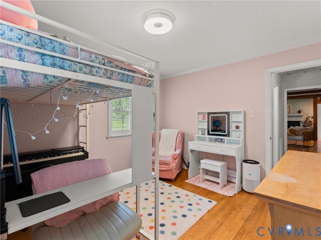 Interior room featuring hardwood flooring, light-colored walls, a ceiling-mounted light fixture, and a window with blinds