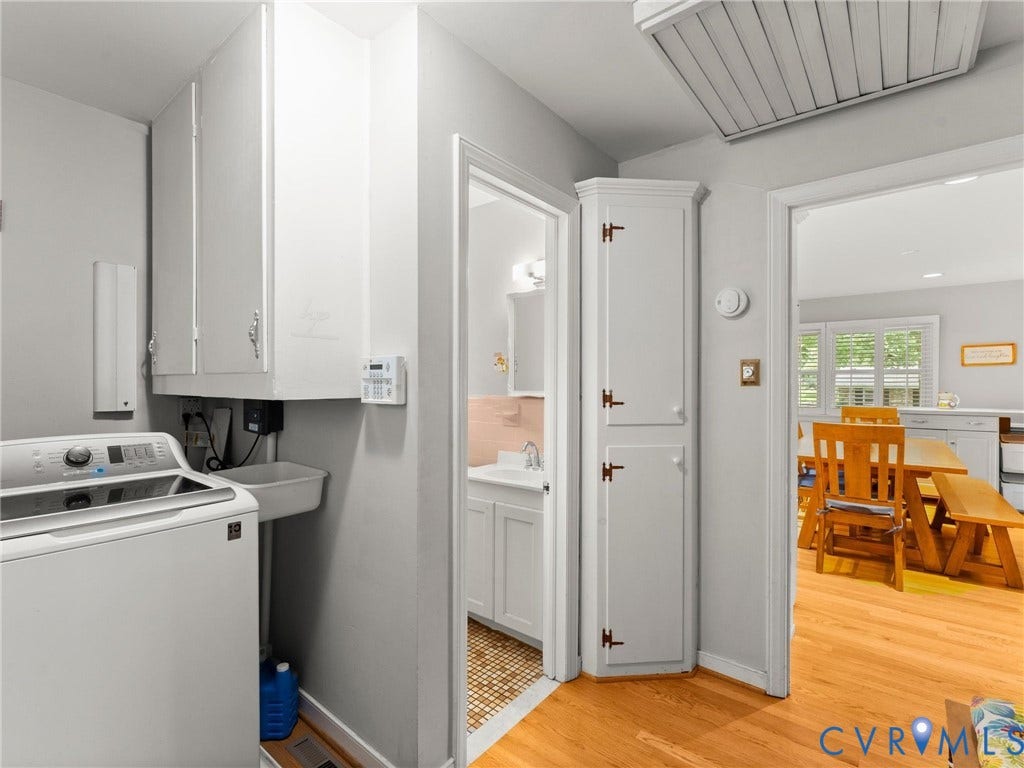 Laundry area featuring white cabinetry, a utility sink, and wood-finish flooring