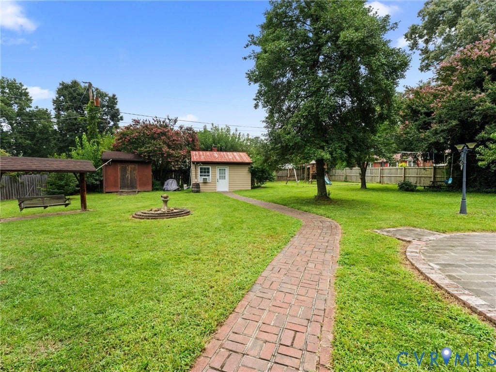 Expansive grounds featuring a manicured lawn, mature shade trees, and a brick-paved pathway