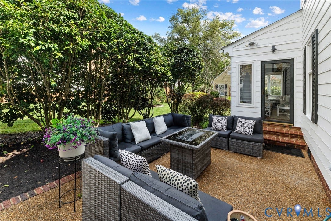 Exterior patio with exposed aggregate surface, bordered by lush landscaping