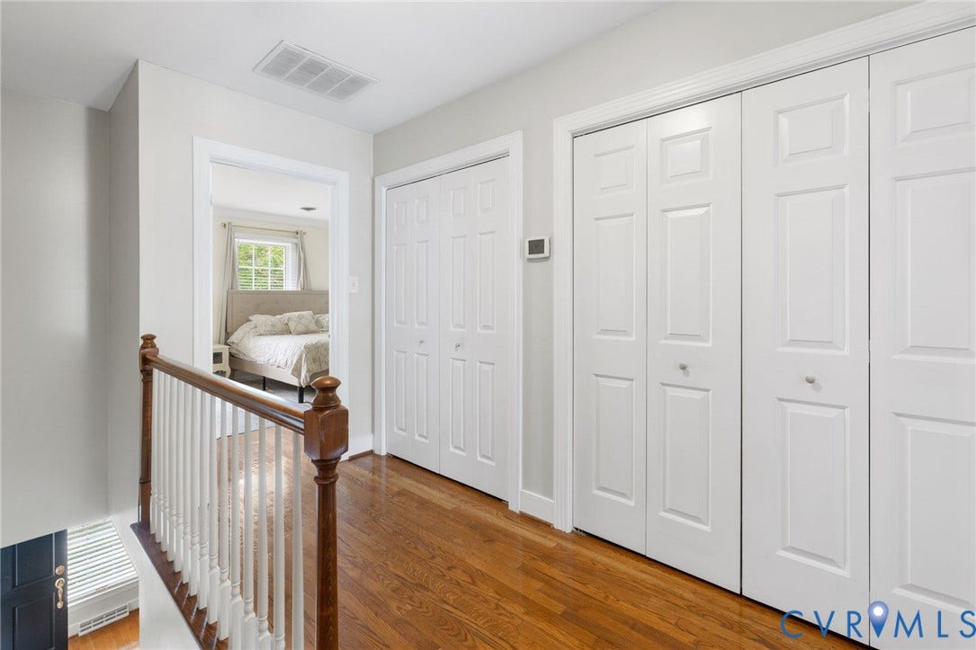 Hardwood flooring, white paneled doors, wood handrail, white balusters, and light gray walls