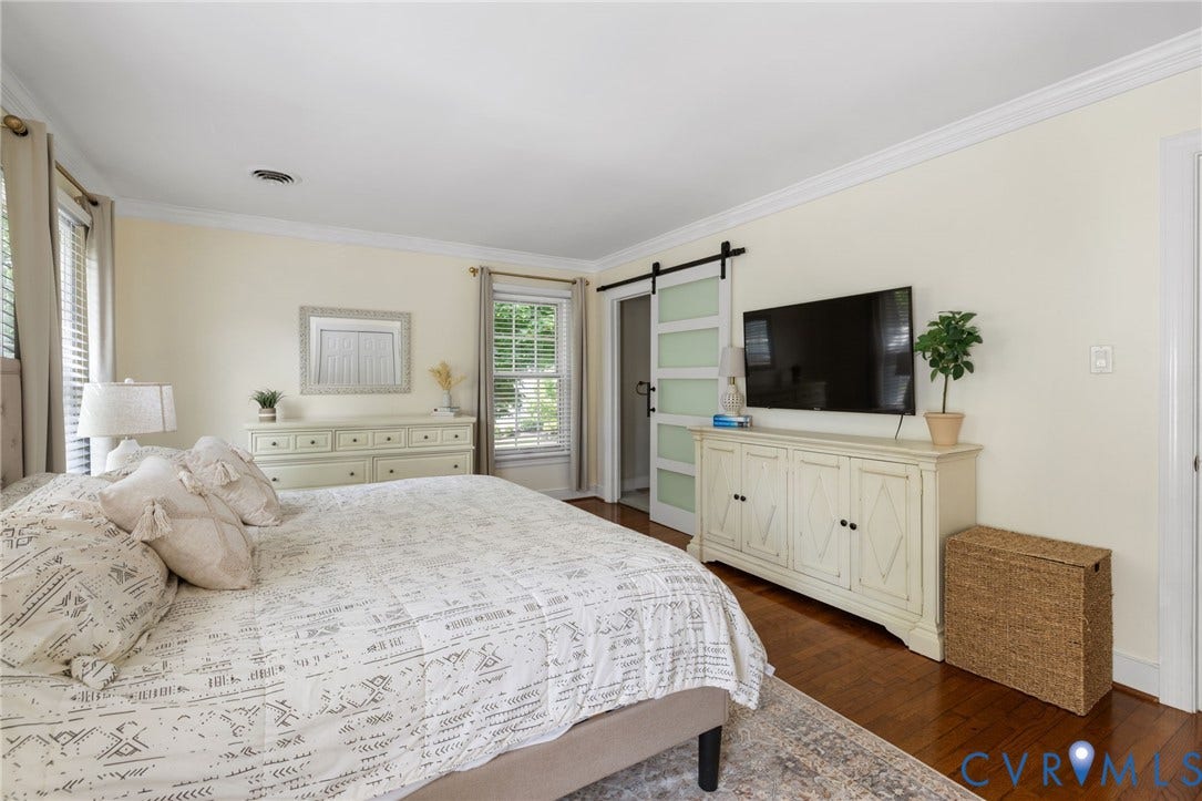 Wood-finish flooring, crown molding, and multiple windows with blinds