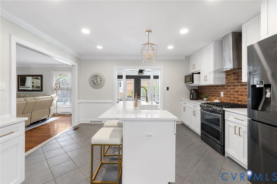 White shaker cabinetry with gold-tone hardware, stainless steel appliances, brick-finish backsplash, white stone countertops, and recessed lighting