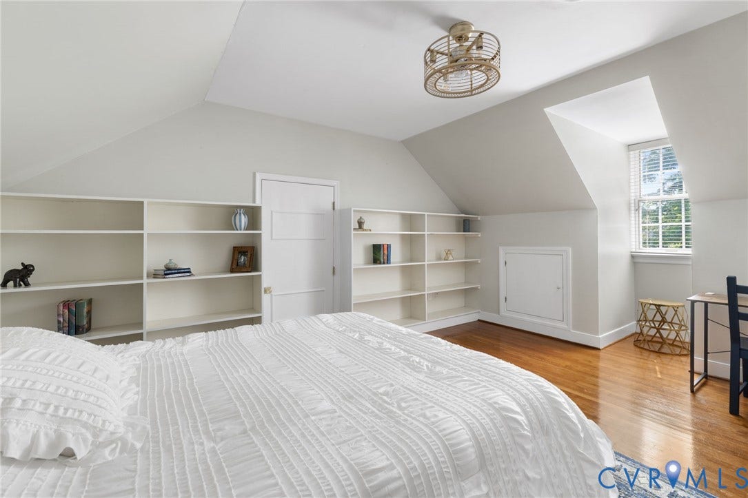 Vaulted ceilings, built-in shelving, hardwood flooring, window with natural light, and a modern ceiling fixture