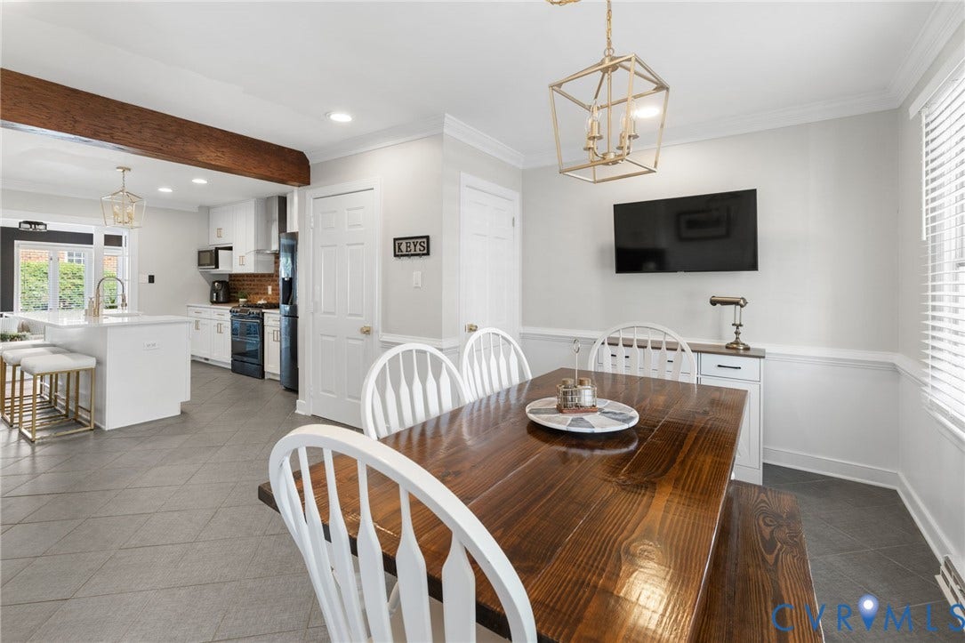 Open-concept dining area with a decorative ceiling fixture, wainscoting, and tile flooring