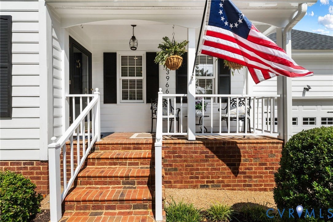 White siding exterior with brick foundation, covered porch, and brick steps with white railings