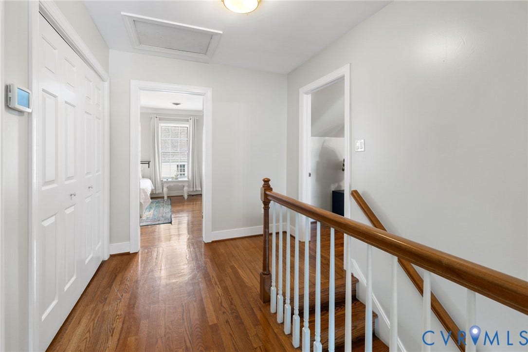 Hardwood flooring, white paneled doors, white walls, and a wood handrail with white balusters