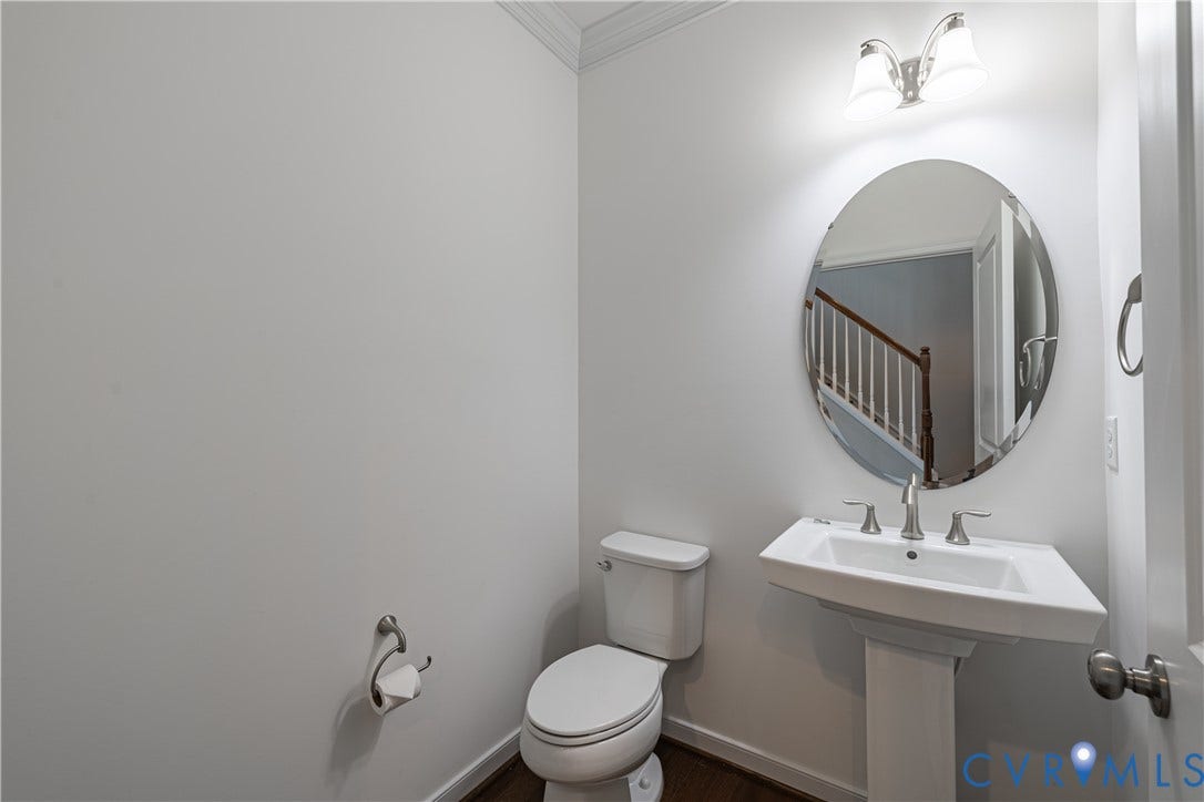Powder room- Pedestal sink , oval mirror, and a vanity light fixture