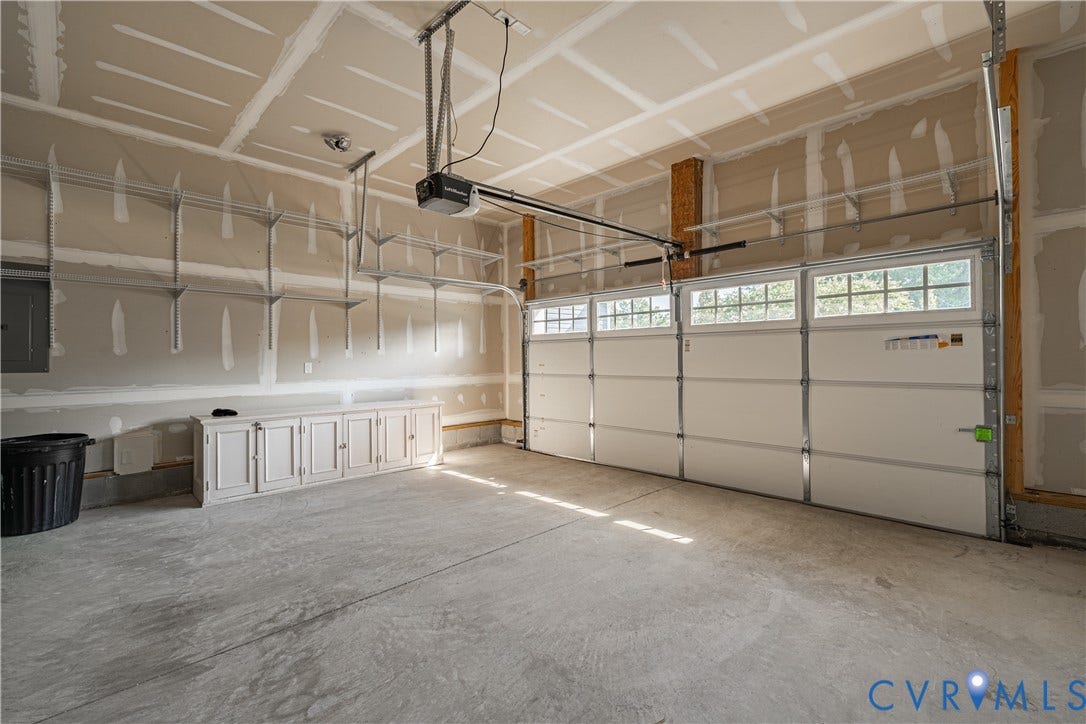 Attached garage with concrete flooring, built-in cabinetry, and integrated overhead storage shelving