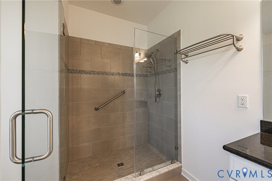 Glass-enclosed shower with tile surround and mosaic accent band