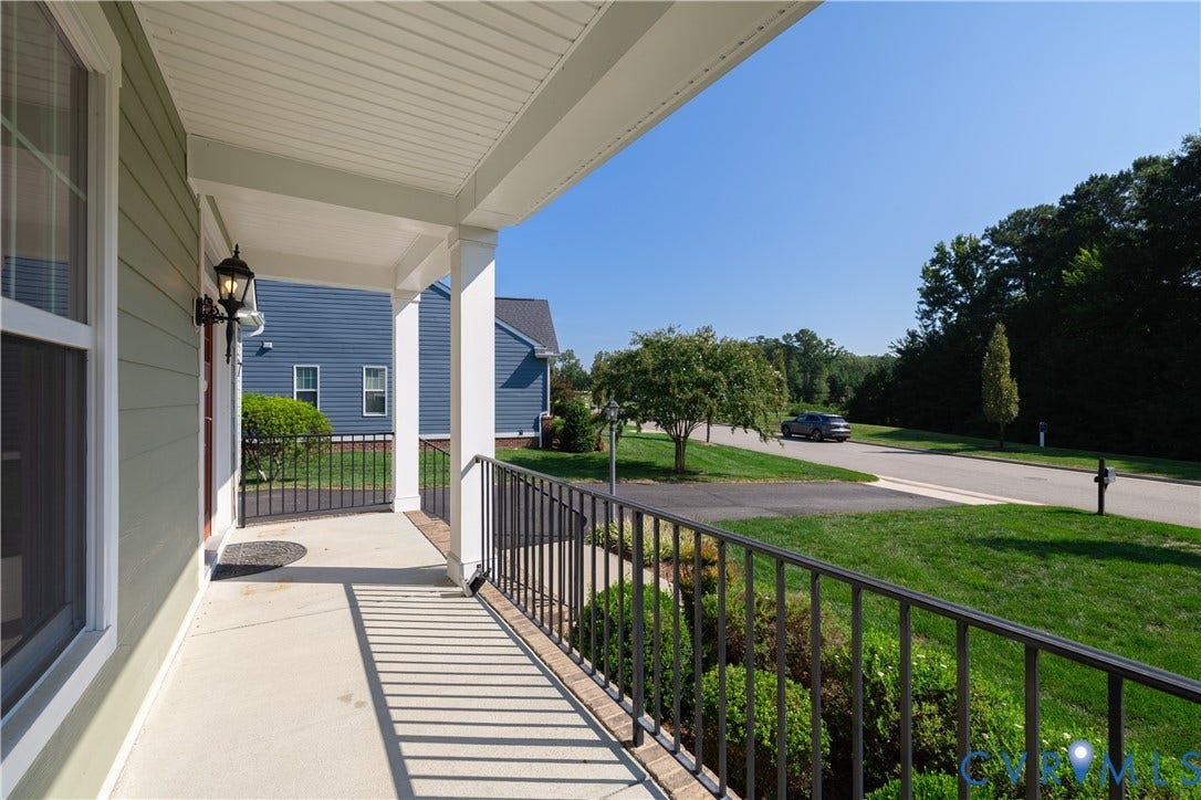 Covered front porch featuring white columns and black metal railings