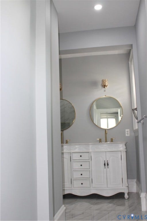 3013 Hawthorne, Richmond, VA 23222 Elegant primary bathroom vanity featuring dual round mirrors with brass-finished hardware, white cabinetry with multiple drawers and cabinet storage, polished brass sconces, and tile flooring throughout