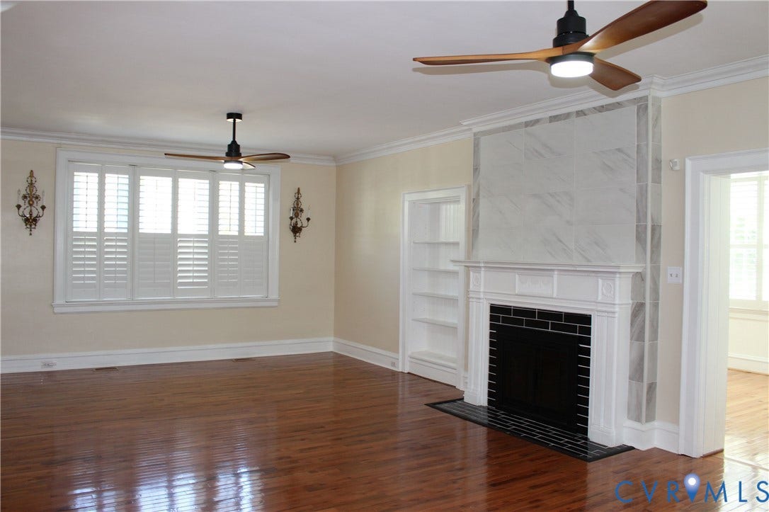 3013 Hawthorne, Richmond, VA 23222 Hardwood flooring, decorative fireplace with tiled surround, built-in shelving, window with plantation shutters, and crown molding