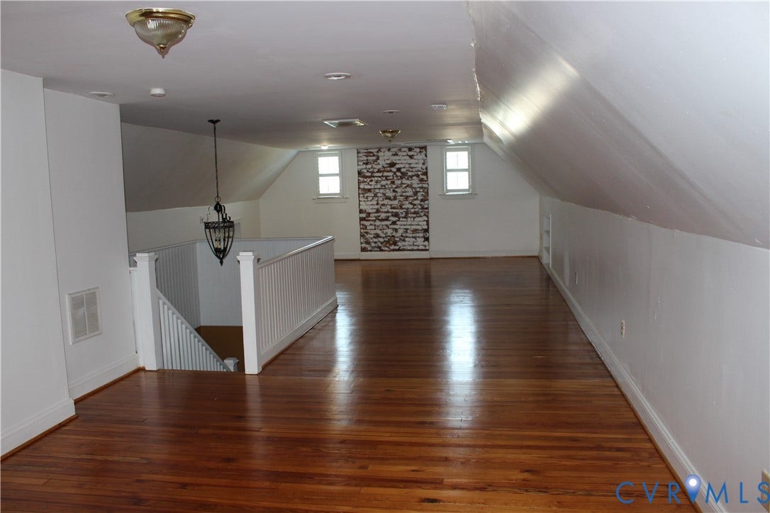 3013 Hawthorne, Richmond, VA 23222 Expansive open room featuring rich wood-finish flooring, white painted walls, and sloped ceilings