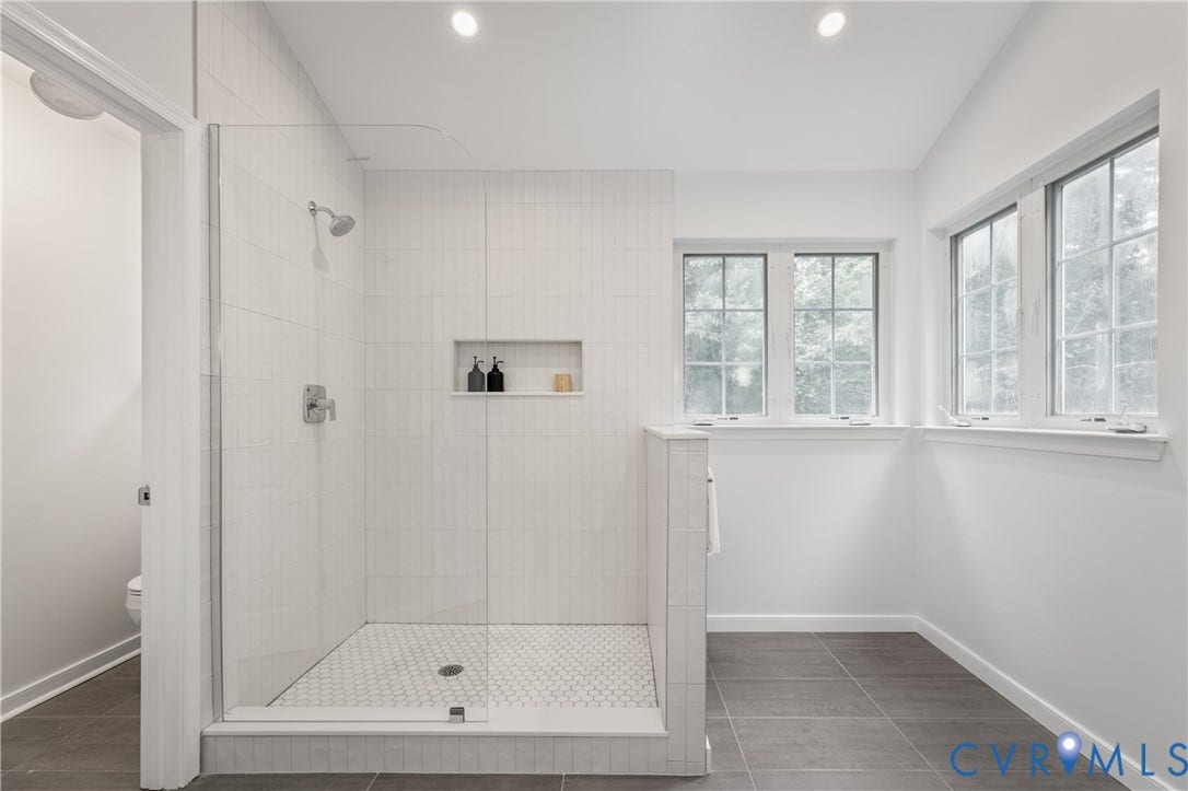 3929 Meadowview Lane, Richmond, VA 23223 Walk-in shower with clear glass enclosure, white subway tile surround, recessed shower niche, and hexagonal mosaic tile floor
