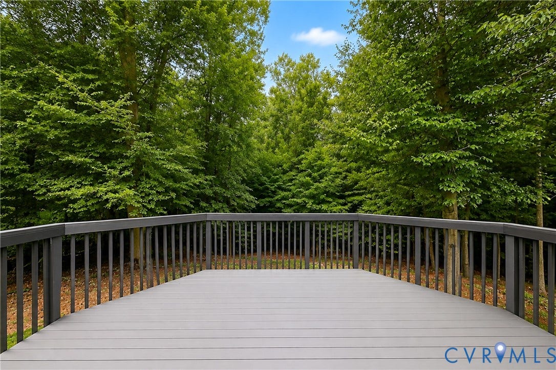 3929 Meadowview Lane, Richmond, VA 23223 Curved outdoor deck featuring composite decking and dark railings, surrounded by mature trees