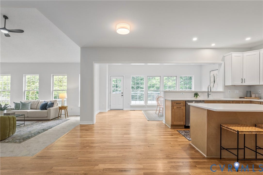 3929 Meadowview Lane, Richmond, VA 23223 Open-concept living area featuring hardwood flooring, white cabinetry with stainless steel appliances, quartz countertops, and a large center island with seating